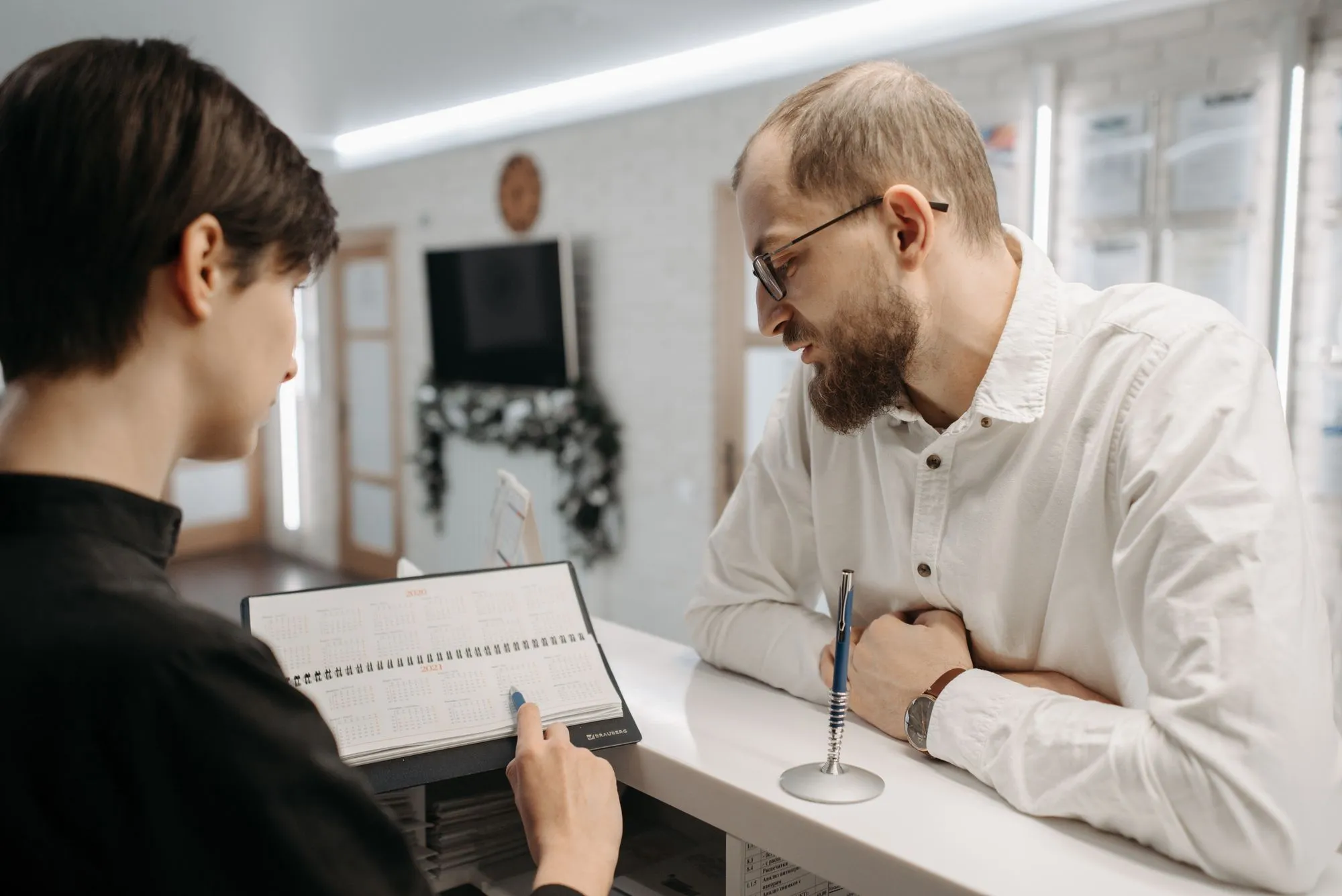 A receptionist reviews the appointment book with a client